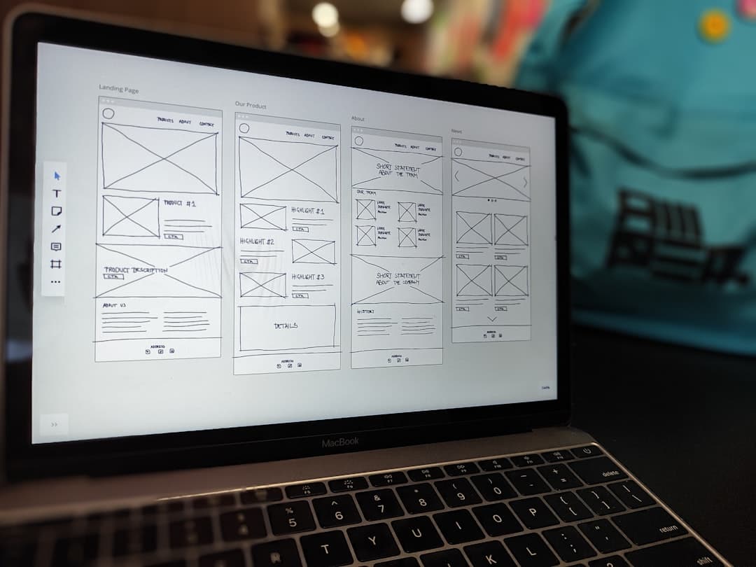 Website wireframe displayed on MacBook screen on office desk