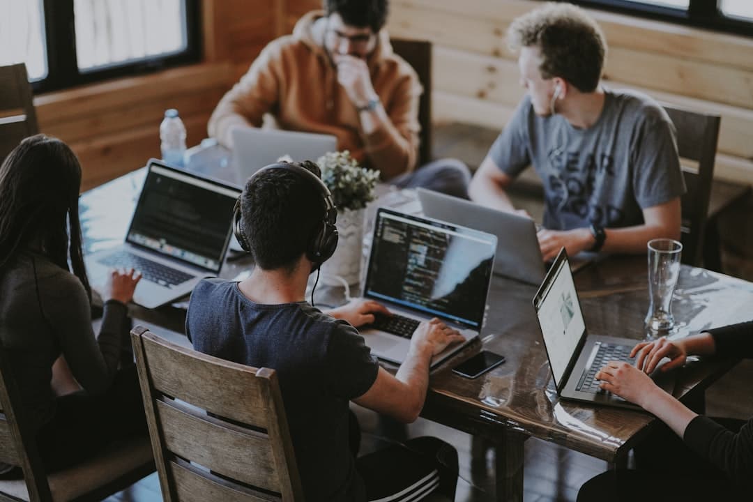 Distributed product team collaborating on laptops around a shared workspace