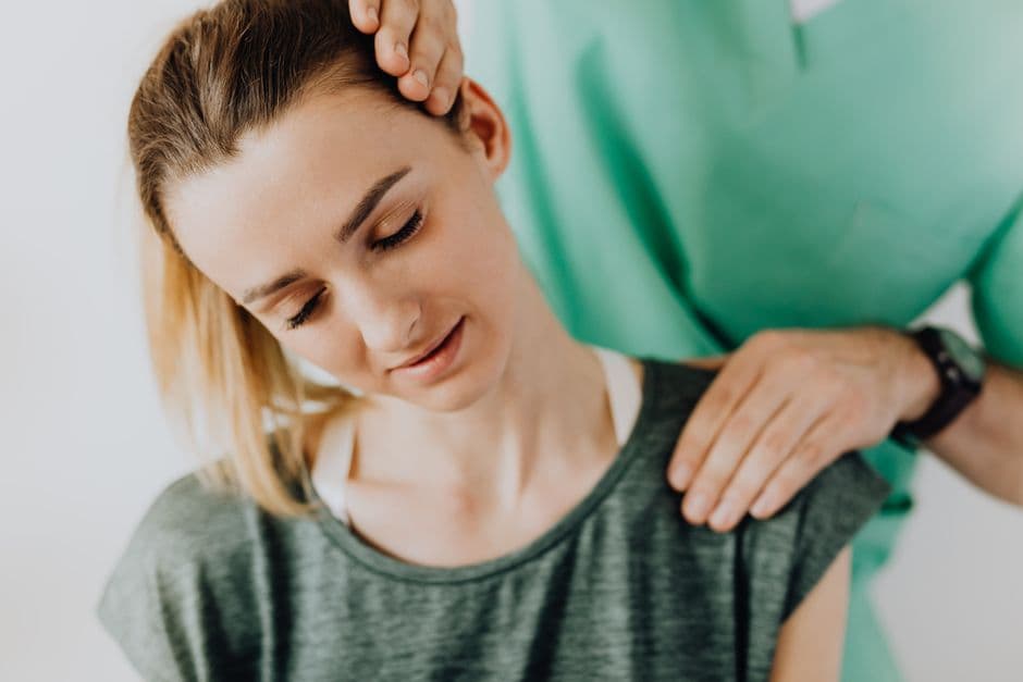 Crop professional male massage therapist in green medical uniform doing therapeutic neck massage on content female patie