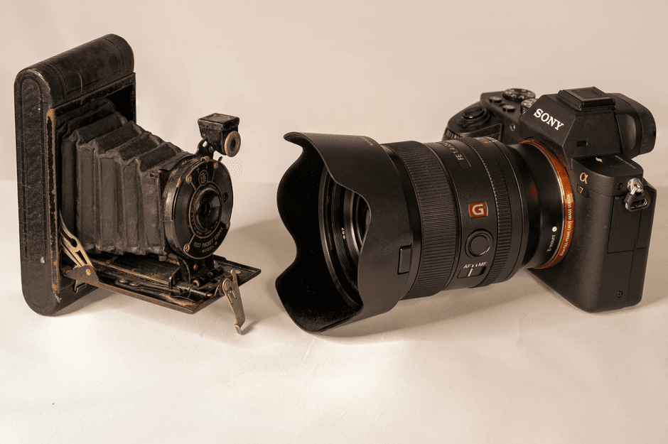 A vintage bellows camera next to a modern DSLR showcasing the evolution of photography technology.
