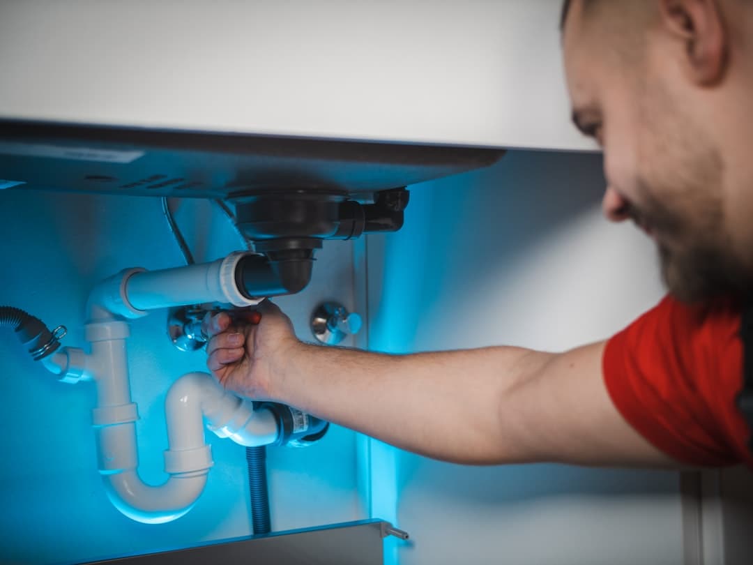 Plumber repairing a pipe, illustrating plumber website design priorities